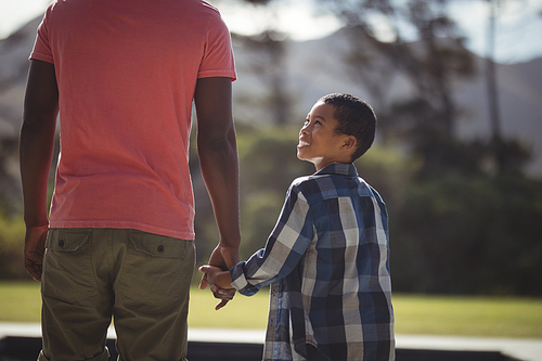 Father and son standing near poolside on a sunny day