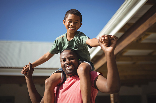 Portrait of happy father carrying son on shoulders