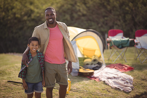 Smiling father and son standing with arm around in park