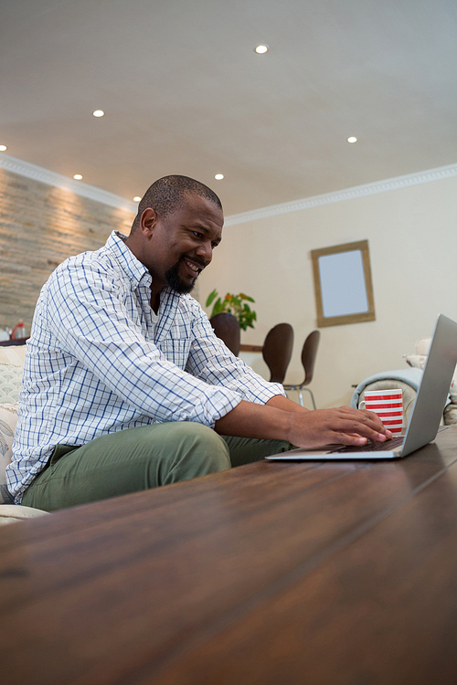 Man using laptop in living room at home