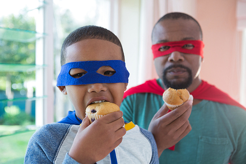 Portrait of father and son having muffin at home