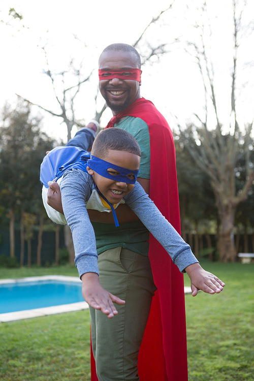 Son and father pretending to be a superhero in garden