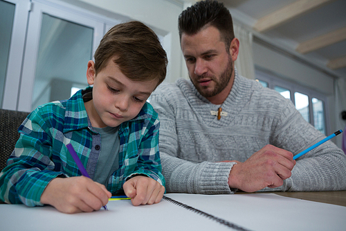 Father assisting son in his studies at table