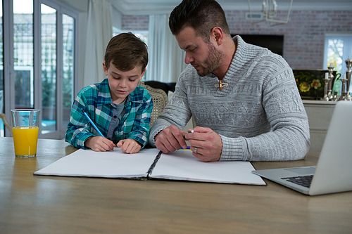 Father assisting son in his studies at table