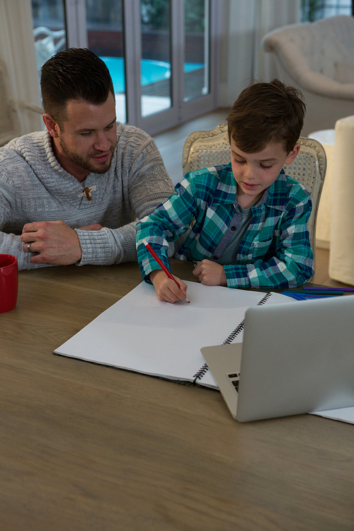 Father assisting son in his studies at table