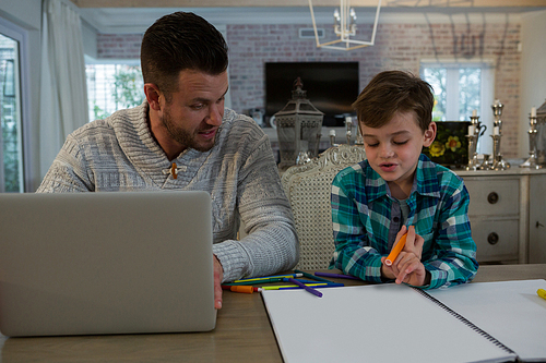 Father assisting son in his studies at table