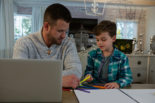 Father assisting son in his studies at table