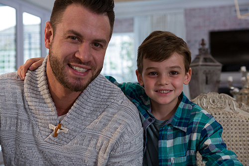 Portrait of happy father and son in living room