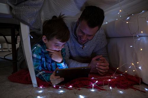 Father and son using digital tablet in bedroom