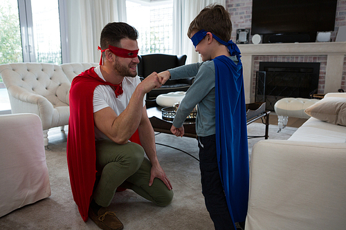 Father and son giving fist bump to each other at home