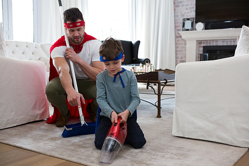 Father and son pretending to be superhero while cleaning floor