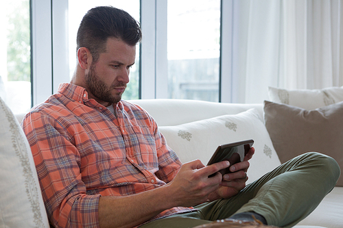 Man using digital tablet in living room at home