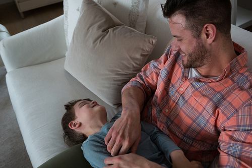 Father tickling his son in living room at home