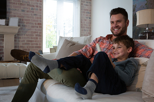 Happy father and son watching television in living room