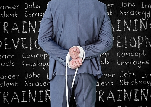 Rear view of businessman with his hands tied with rope against business terms in background