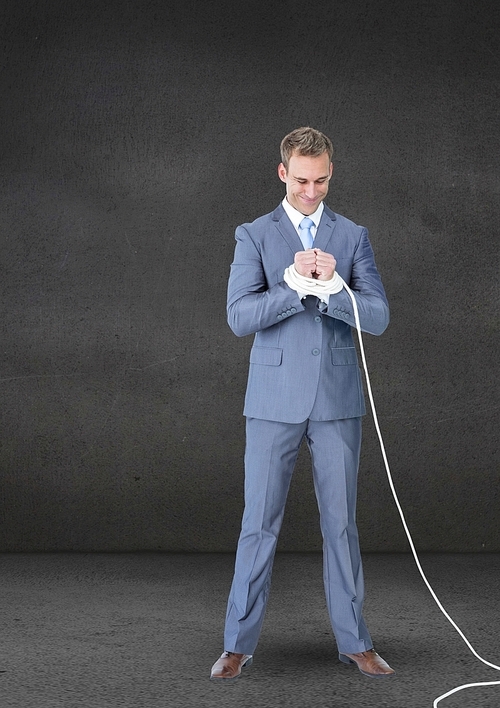 Businessman standing and his hands tied with a rope against grey background