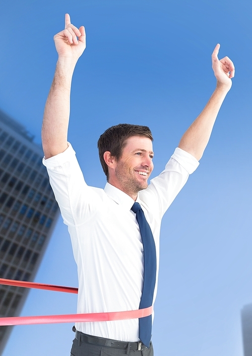 Composite image of businessman celebrating at finish line against city building in background