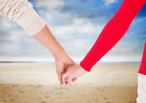 Close-up of newly wed couple holding hands on beach
