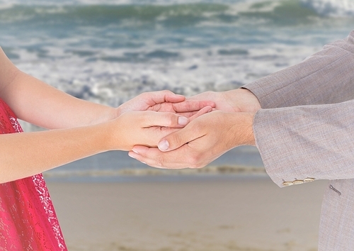 Close-up of couple holding hands on beach