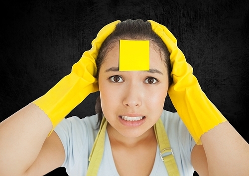 Stressed cleaner with sticky note stuck o her face against black background