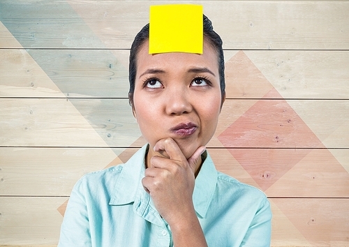 Digital composition of frustrated woman with sticky note stuck on her head against wooden background