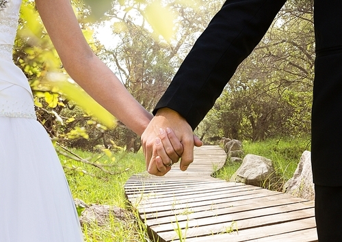 Close-up of newly wed couple holding hands in the park