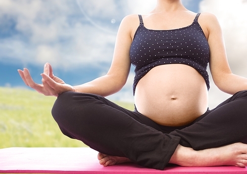 Digital composition of pregnant woman meditating with greenery in background