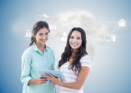 Digital composition of female executives holding digital tablet with networking icons and cloud in background