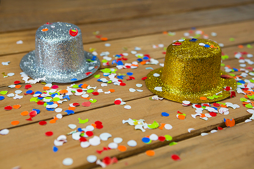 Close-up of golden and silver hat with confetti on wooden surface