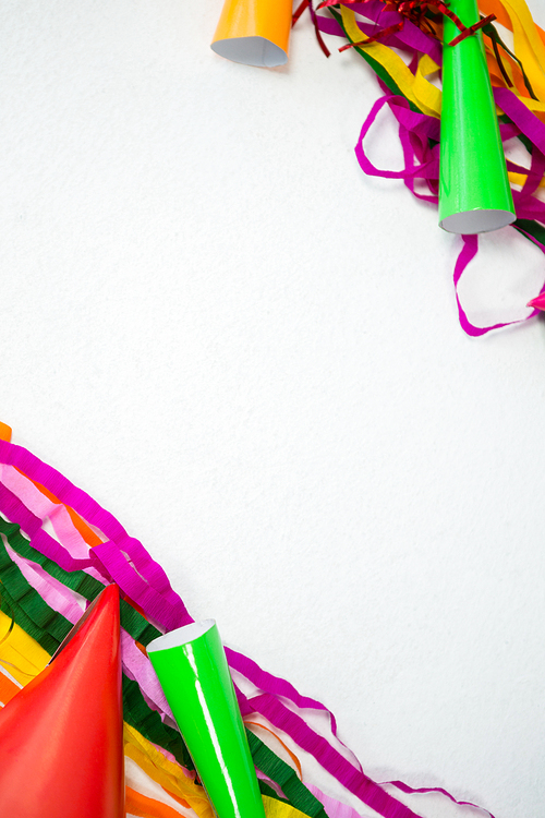 Overhead of colorful streamers and party hat on white background