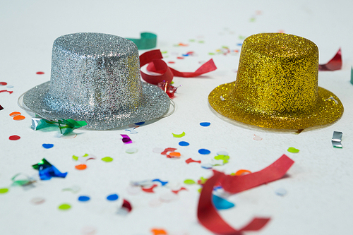 Close-up of golden and silver hat with confetti on white background