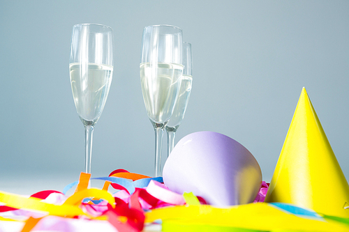 Champagne flutes with party hat and streamers on white background