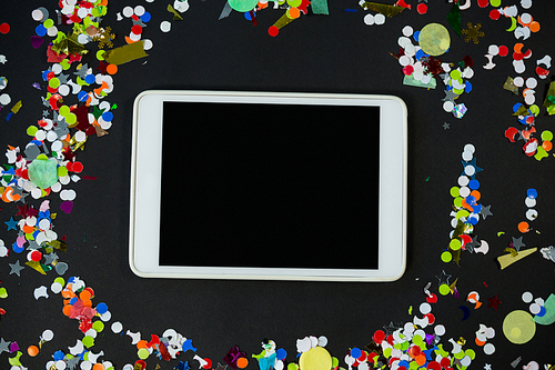 Overhead of digital tablet surrounded by confetti
