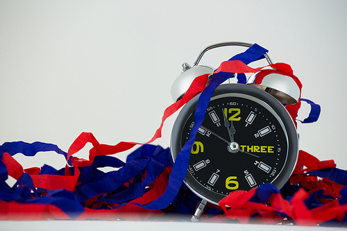 Close-up of alarm clock and streamers against white background