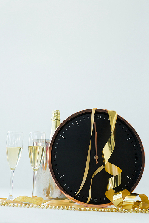 Close-up of champagne with clock and glass on white background