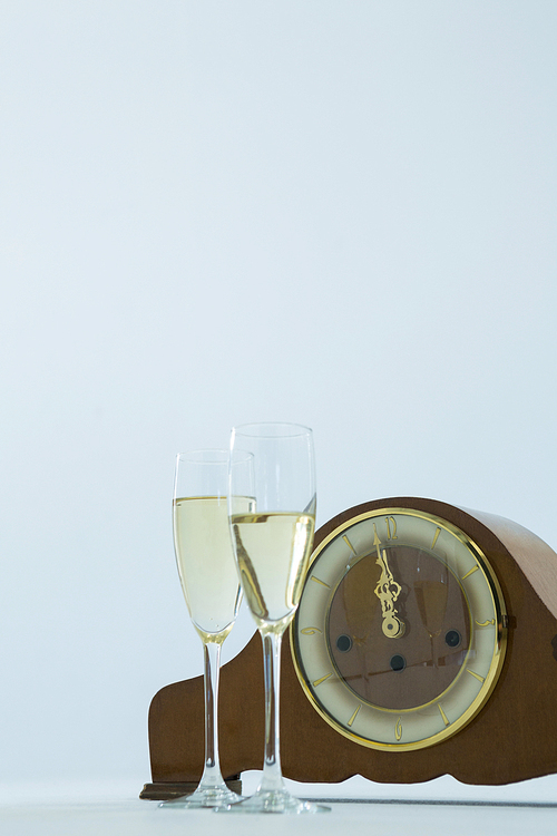 Close-up of champagne glass and clock on white background