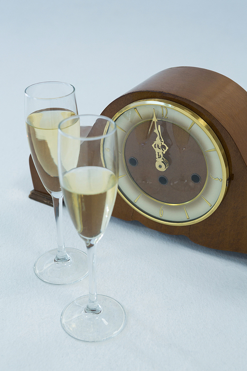 Close-up of champagne glass and clock on white background