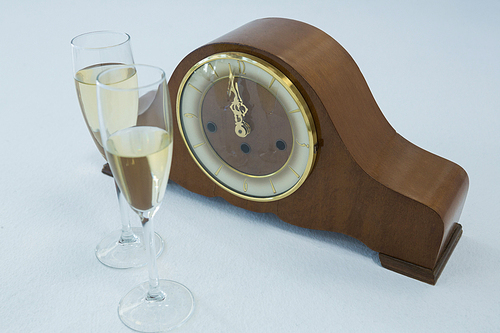 Close-up of champagne glass and clock on white background