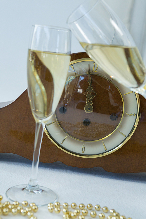 Close-up of champagne glass and clock on white background