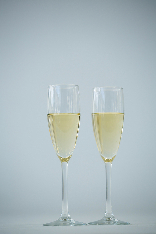 Close-up of two champagne flutes against white background