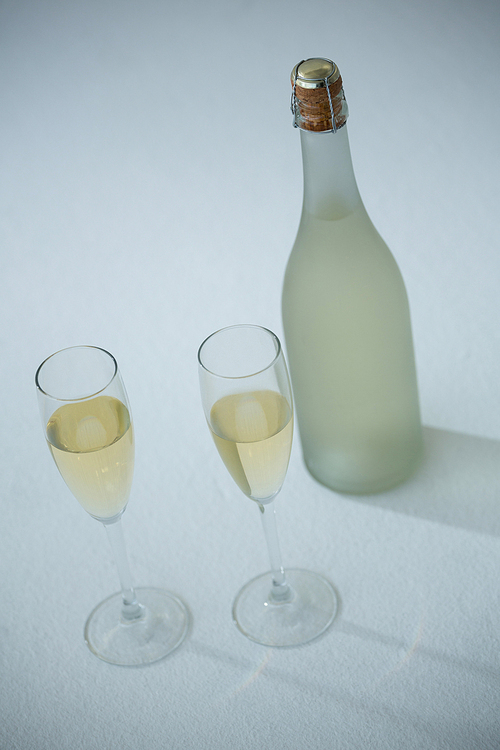 Glass of champagne with champagne bottle on white background