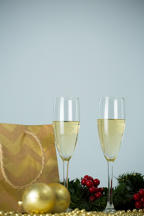Close-up of champagne flute and christmas decoration against white background