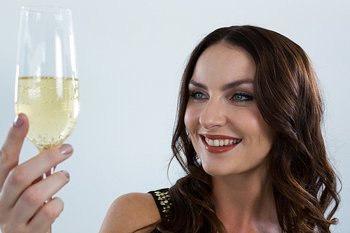 Smiling woman holding glass of champagne against white background