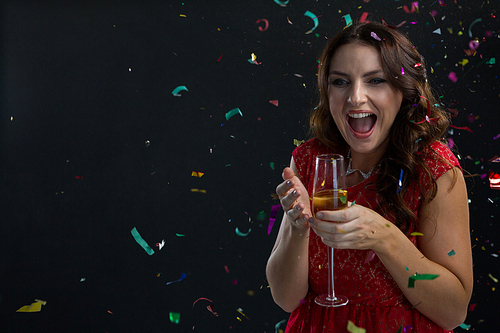Happy woman celebrating the New year with falling confetti streamers and champagne