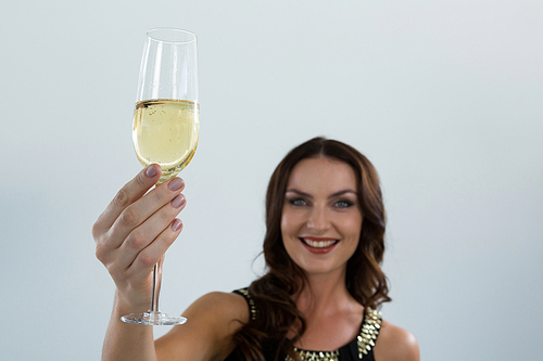 Portrait of smiling woman holding glass of champagne against white background