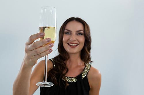Portrait of smiling woman holding glass of champagne against white background