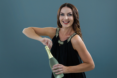 Portrait of smiling woman opening bottle of champagne