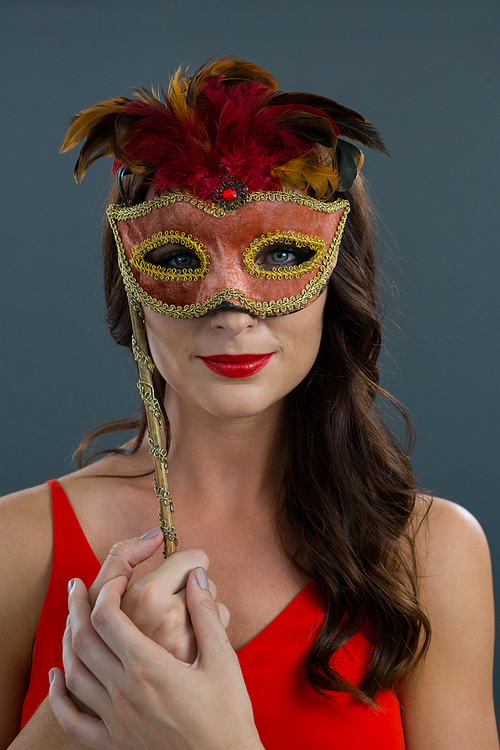 Portrait of beautiful woman wearing masquerade mask against black background
