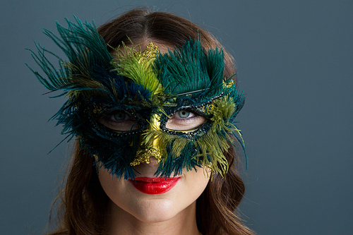 Portrait of Woman wearing masquerade mask against black background