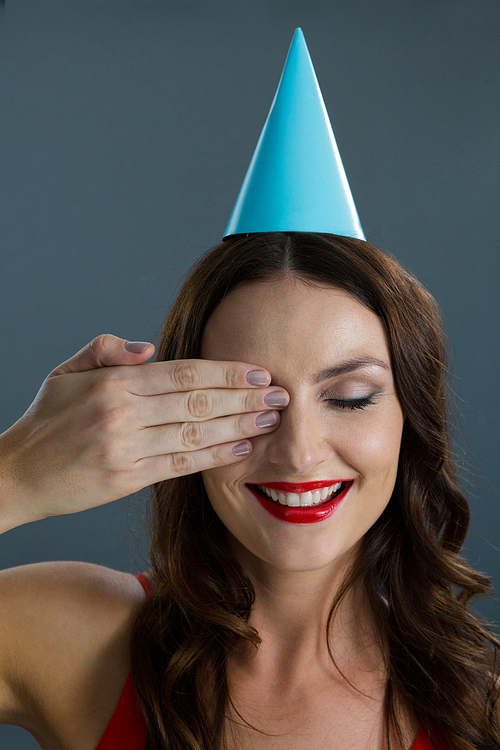 Woman in party hat closing her eyes against black background